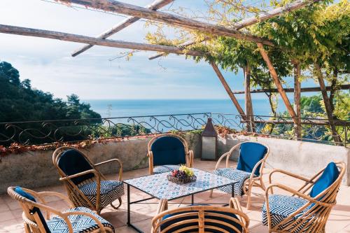 a patio with a table and chairs and the ocean at L'Olearia Luxury Country Villa in Amalfi Coast in Maiori