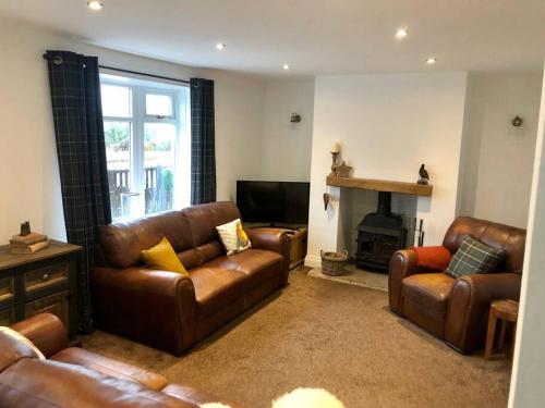 a living room with leather furniture and a fireplace at ValleyView Cottage-Cosy, Rustic Home - Log Burner in Ushaw Moor