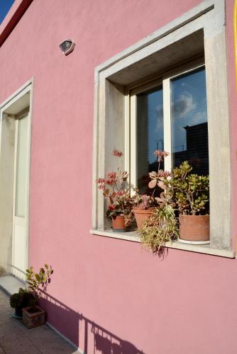 a pink building with potted plants in a window at Il giardino delle zagare - miniappartamento tra Etna e mare in Riposto
