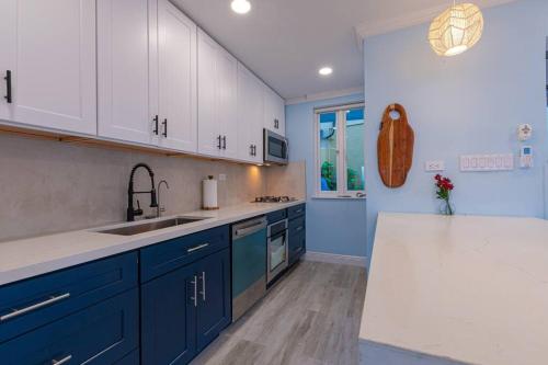 una cocina con armarios azules y blancos y fregadero en Harbour Mews - Oceanfront Townhouse en Nassau