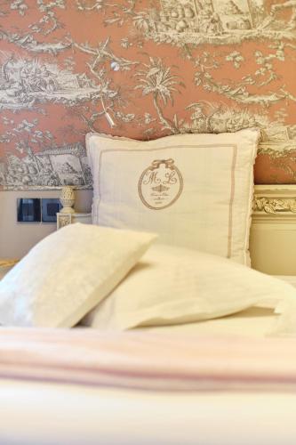 a bed with a white pillow and a wall at Au Petit Manoir in Socx