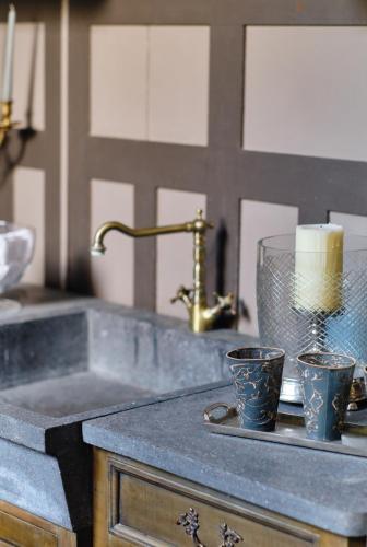 a kitchen sink with two cups and a candle at Au Petit Manoir in Socx