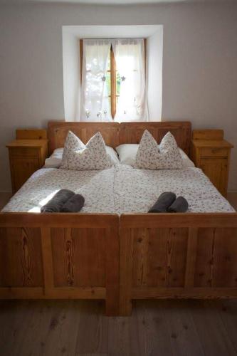 a large wooden bed in a bedroom with a window at Juvanova hiša (all house) in Luče