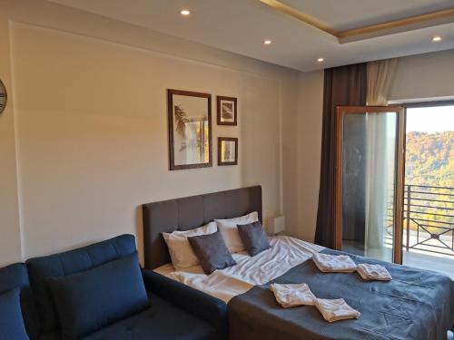 a bedroom with a bed and a couch and a window at SkyKop Apartman L21 in Kopaonik