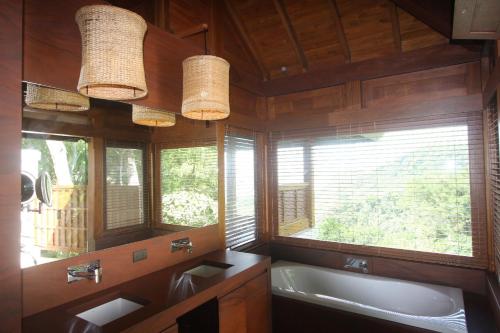 a bathroom with a tub and a sink and two windows at Canta La Rana in Bejuco