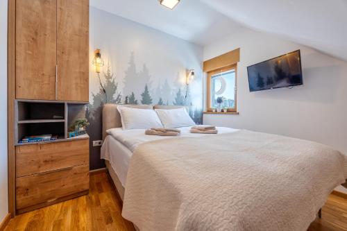 a bedroom with a large bed with a tv on the wall at Apartman Prima Plus in Zlatibor