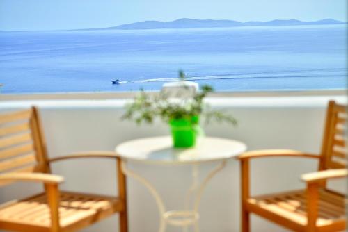 a table with two chairs and a vase with flowers on it at Paolas Sunset in Agios Stefanos