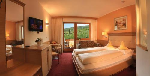 Habitación de hotel con cama grande y ventana en Hotel Eichenhof, en Tirolo