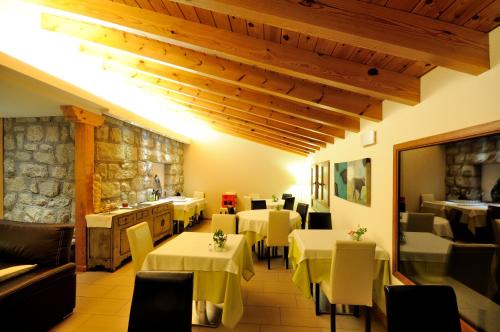 un restaurante con mesas y sillas blancas y una pared de piedra en Hotel Rural Las Rozuelas en Cercedilla