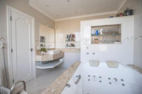 baño blanco grande con bañera y lavamanos en Pousada Recanto Jota Ge, en Paraty
