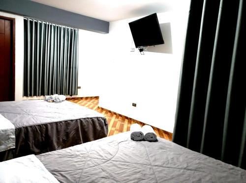 Habitación de hotel con 2 camas y TV en Tumalki Rooms, en Trujillo