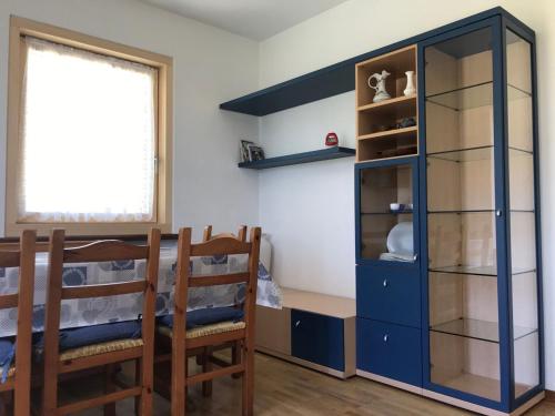 una sala da pranzo con un mobile blu e due sedie di Appartamenti Perlot Marco a Fai della Paganella
