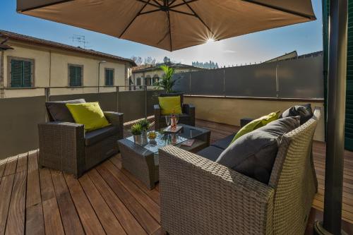 a patio with two chairs and an umbrella on a deck at CHIANTI LUXURY APARTMENTS GREVE in Greve in Chianti