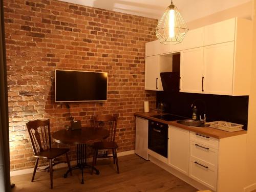 eine Küche mit einem Tisch und einem TV an einer Backsteinwand in der Unterkunft Solaris Apartments Self-Check-In in Oppeln