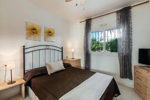 een slaapkamer met een bed, een televisie en een raam bij Perfect Family Apartment in Acapulco Playa, Nerja in Nerja