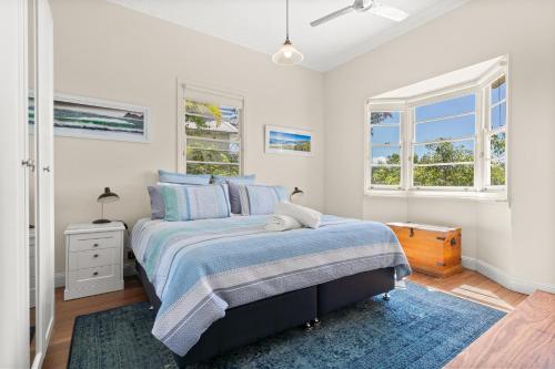1 dormitorio con 1 cama y 2 ventanas en Wambiri on Lighthouse Road en Byron Bay