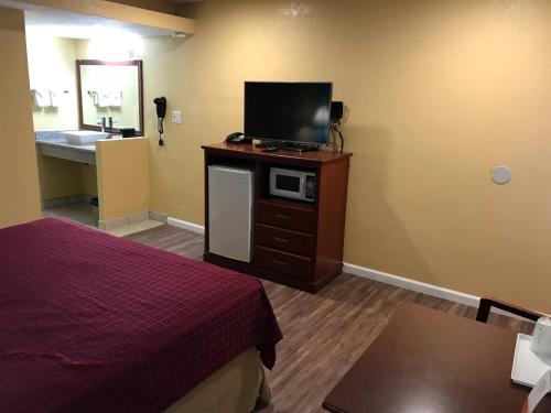 a room with a bed and a television on a dresser at Travelodge by Wyndham San Diego SeaWorld in San Diego