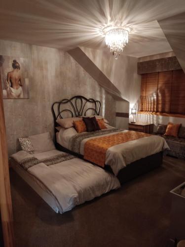 a bedroom with two beds and a chandelier at No ' 9 The Cooperage' in Auchleven