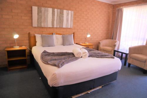 a bedroom with a large bed with two towels on it at Golden Chain Aalana Motor Inn in Cowra