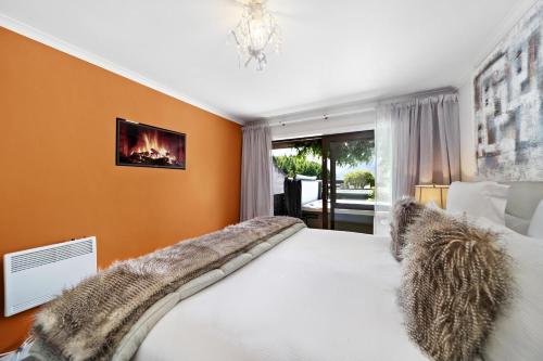 a bedroom with a large bed with a fireplace at Distinctive Alpine Meadows in Queenstown
