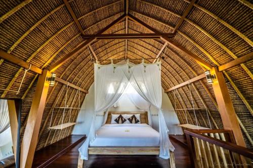 a bedroom with a bed in a straw roof at Bunga Laut Bungalow in Amed