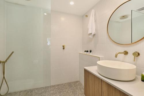 a white bathroom with a sink and a shower at Spinnaker Quays in Mooloolaba