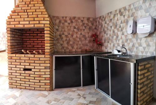 a kitchen with a counter and a brick wall at Chaleville Coqueiro 1001 in Luis Correia
