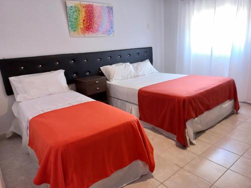 a bedroom with two beds with red and white sheets at Ayres del Rio in Formosa