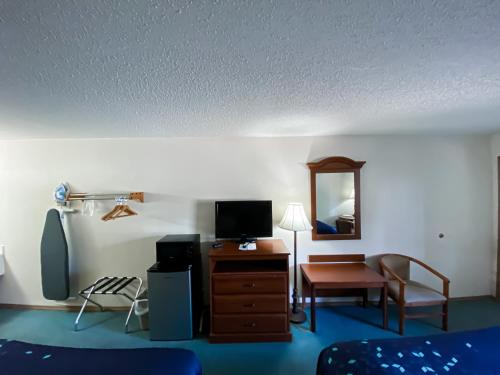 a room with a desk with a television and a chair at Green Gables Inn in Branson
