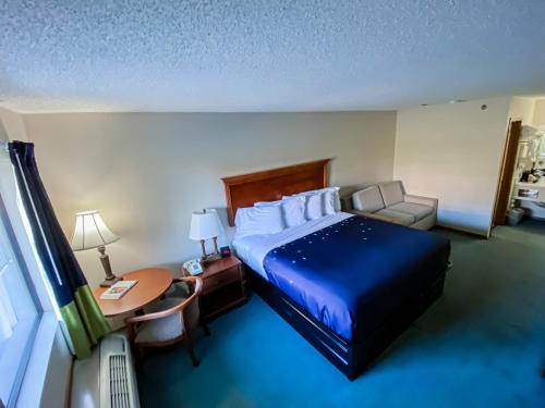a hotel room with a bed and a desk and a table at Green Gables Inn in Branson