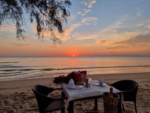 a table on the beach with the sunset in the background at Sahaa Beach Resort in Sihanoukville