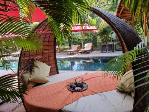 a wicker chair with a plate of food on it next to a pool at Sahaa Beach Resort in Sihanoukville