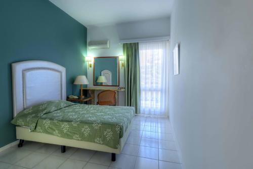 a bedroom with a bed with a green comforter at Palmariva Beach Hotel in Eretria