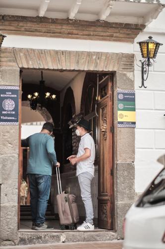 two men standing in a doorway with their luggage at Land of the Sun Hotel & Spa in Cotacachi