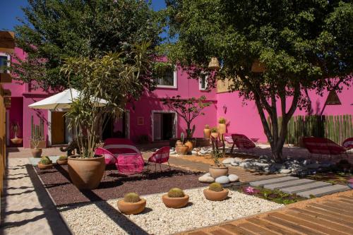 um edifício cor-de-rosa com cadeiras e plantas à sua frente em Casa Rosamate em Oaxaca de Juárez