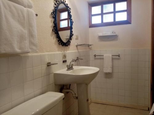 a white bathroom with a sink and a mirror at Land of the Sun Hotel & Spa in Cotacachi