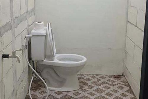 a bathroom with a toilet with a hose at Rocky Guest House Syariah Mitra RedDoorz in Sungai Lutus