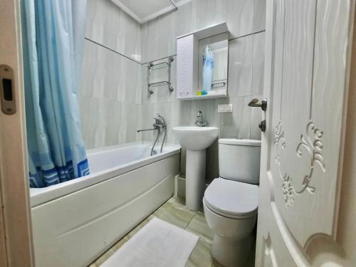 uma casa de banho com um lavatório, um WC e uma banheira em Квартира на Тулебаева em Almaty