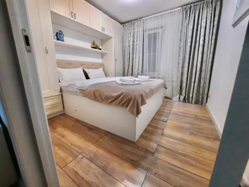 um pequeno quarto com uma cama e piso em madeira em Квартира на Тулебаева em Almaty