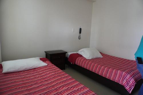 a room with two beds and a phone on the wall at Hotel Alta Vista Campestre in Tibasosa