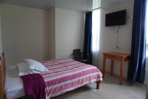 a bedroom with a bed and a desk and a television at Hotel Alta Vista Campestre in Tibasosa