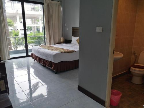 a bedroom with a bed and a bathroom with a window at Platinum Place in Bangkok