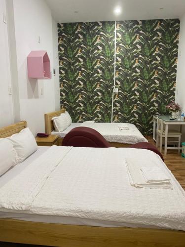 a bedroom with two beds and a green wall at Melody Homestay Quy Nhơn in Quy Nhon