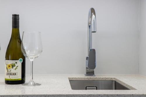 a bottle of wine and a wine glass next to a sink at Suncourt Hotel & Conference Centre in Taupo
