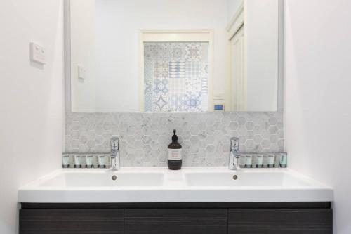 a bathroom with a white sink and a mirror at The MOST alluring getaway in Hunter Valley in Mount View