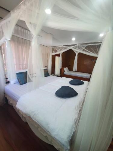 a bedroom with a white canopy bed with pillows on it at น่านสุขโข โฮมสเตย์ in Ban Na Tho