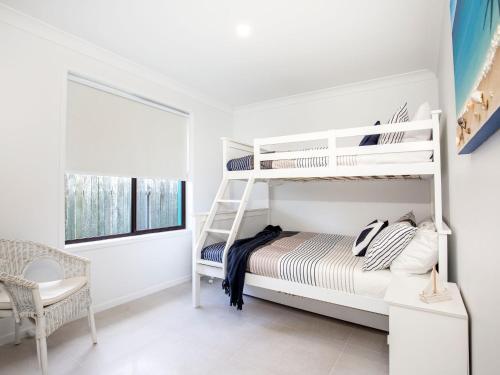 a white bedroom with a bunk bed and a window at Sandy Feet Retreat I Pet Friendly I 1 Min Walk to Beach in Currarong