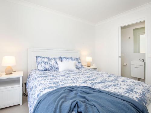 a white bedroom with a bed with a blue comforter at Sandy Feet Retreat I Pet Friendly I 1 Min Walk to Beach in Currarong