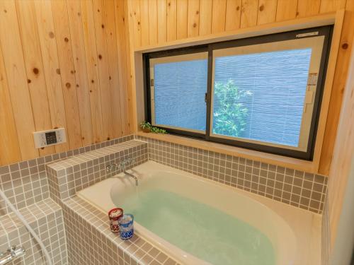 a bathroom with a tub with a window at YADOYA Ryusenjicho in Tokyo