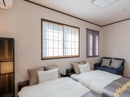 a bedroom with two beds and a blue chair at YADOYA Ryusenjicho in Tokyo